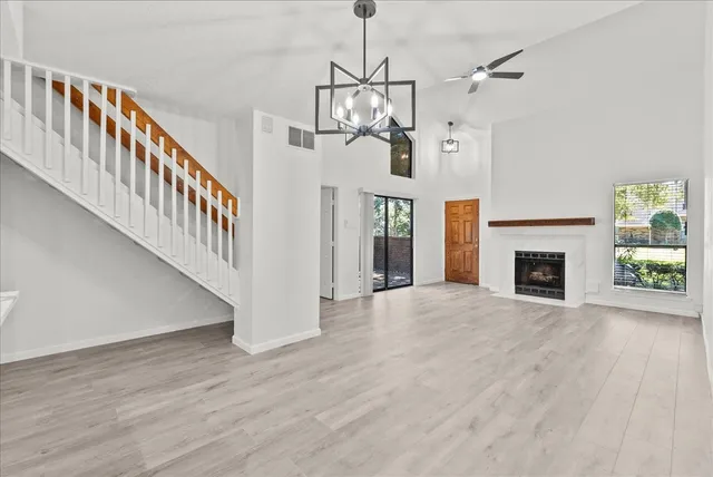 a view of a livingroom with wooden floor fireplace stairs and windows
