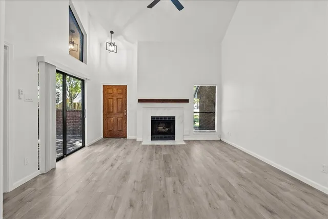a view of an empty room with wooden floor fireplace and a window