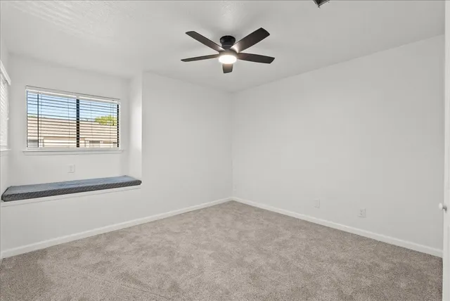 an empty room with ceiling fan and window