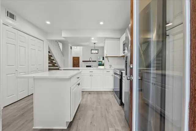 a kitchen with white cabinets and refrigerator