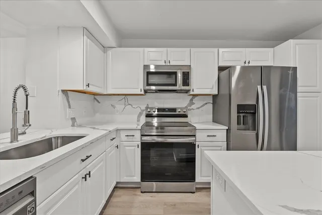 a kitchen with white cabinets and stainless steel appliances
