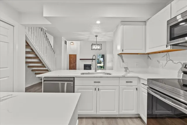 a kitchen with white cabinets appliances and a sink