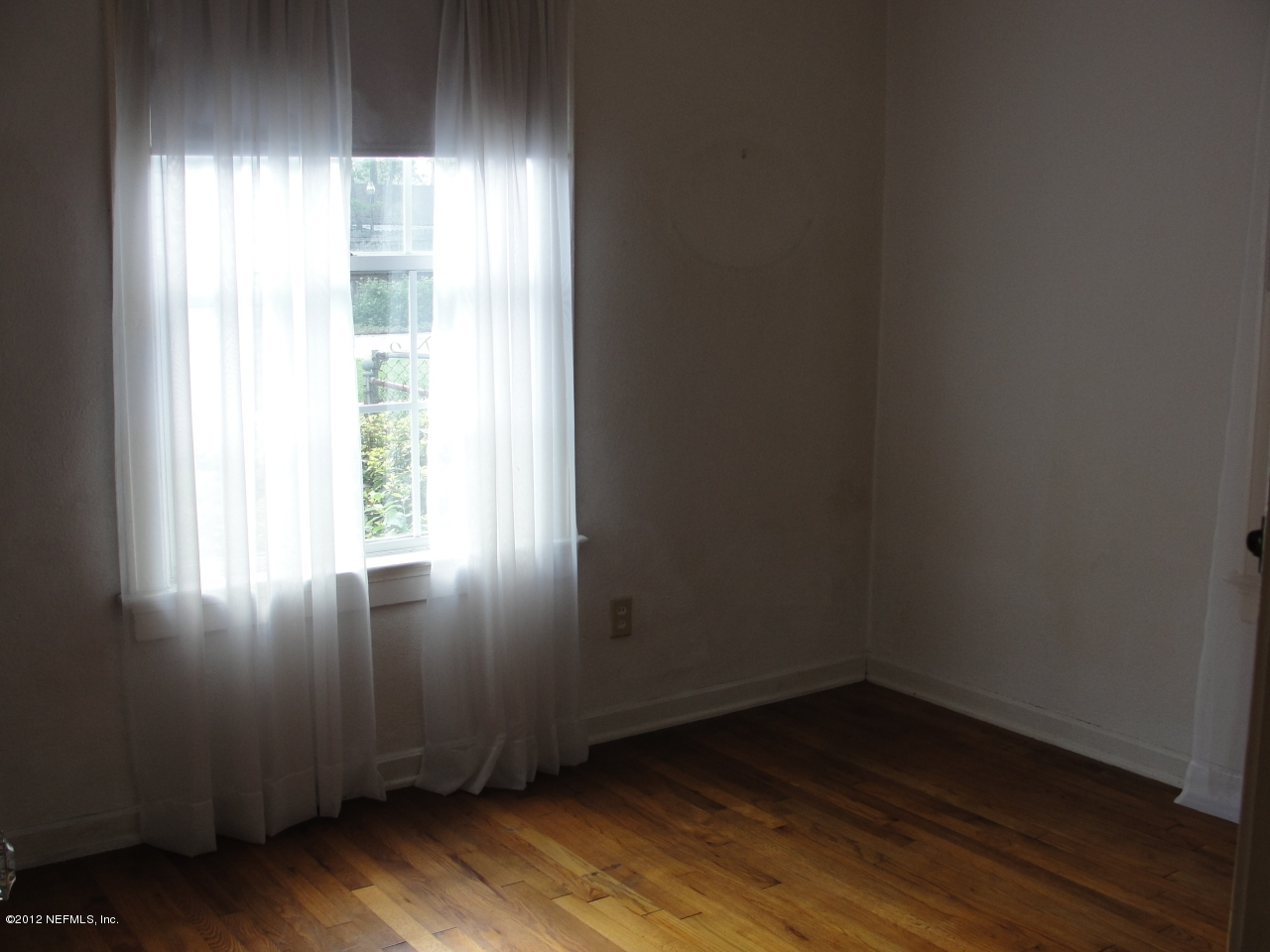 4656 Manchester Road Jacksonville, FL 32210 - Photo 13 of 31 an empty room with wooden floor and windows with curtains