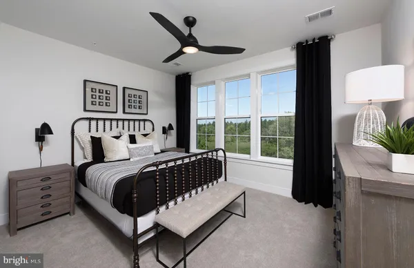 a spacious bedroom with a bed painting on wall and a large window
