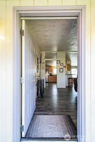 a hallway with hardwood floor and a view of living room