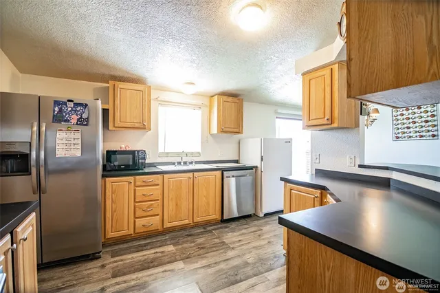 a kitchen with stainless steel appliances granite countertop a sink refrigerator stove and microwave