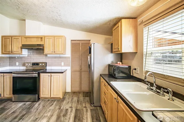 a kitchen with stainless steel appliances granite countertop a sink stove and refrigerator