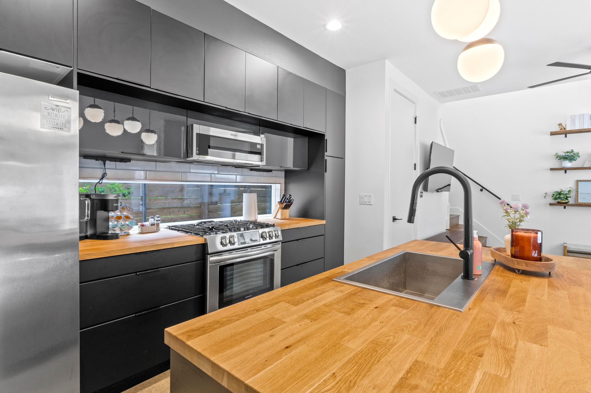 1706 Perez Street, Unit 2 Austin, TX 78721 - Photo 12 of 29 Modern kitchen with sleek black cabinetry, stainless steel appliances, and warm wood countertops.