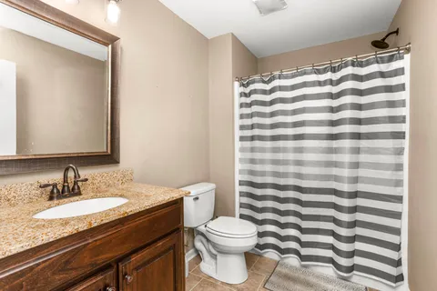 a bathroom with a granite countertop sink toilet and shower