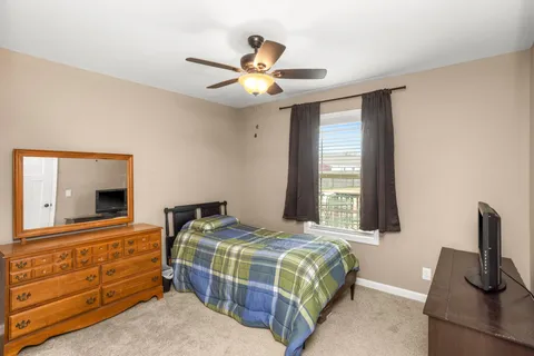 a bedroom with a bed and a flat tv screen on dresser