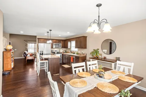 a dining room with wooden floor a chandelier a wooden table and chairs