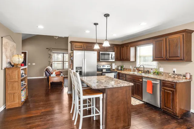 a kitchen with stainless steel appliances granite countertop wooden floor sink stove and wooden cabinets