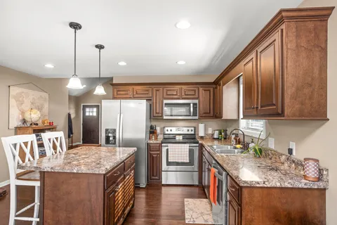 a kitchen with stainless steel appliances granite countertop a sink a stove and a wooden floors