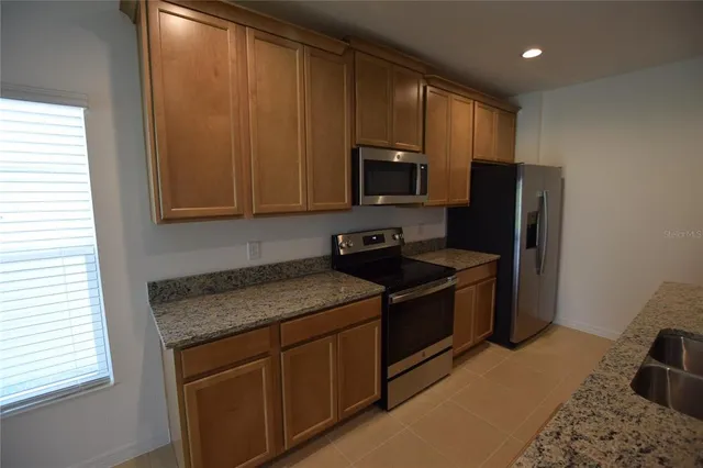 a kitchen with granite countertop stainless steel appliances a stove microwave and refrigerator