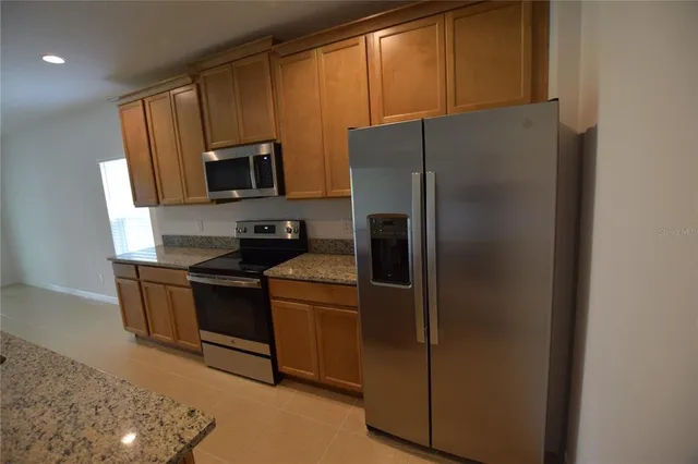 a kitchen with stainless steel appliances granite countertop a refrigerator stove and microwave