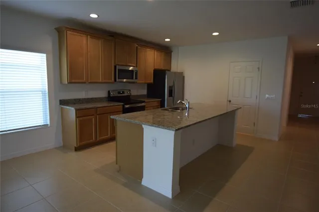 a kitchen with kitchen island granite countertop a sink counter top space appliances and cabinets