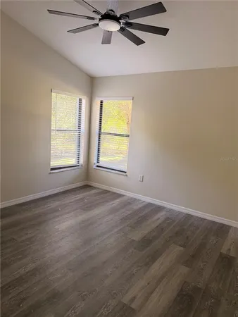 an empty room with wooden floor windows and ceiling fan