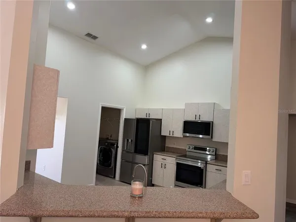 a kitchen with stainless steel appliances kitchen island granite countertop a refrigerator and a stove top oven
