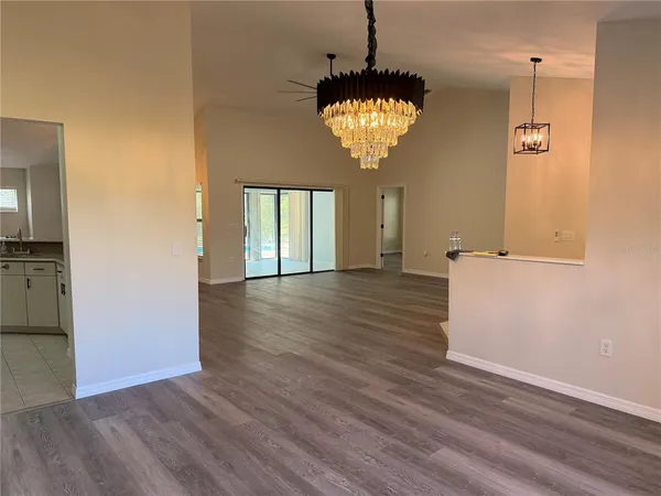 a view of a hallway with wooden floor and chandelier