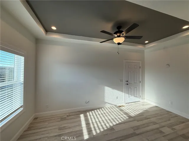 a view of empty room with wooden floor and fan