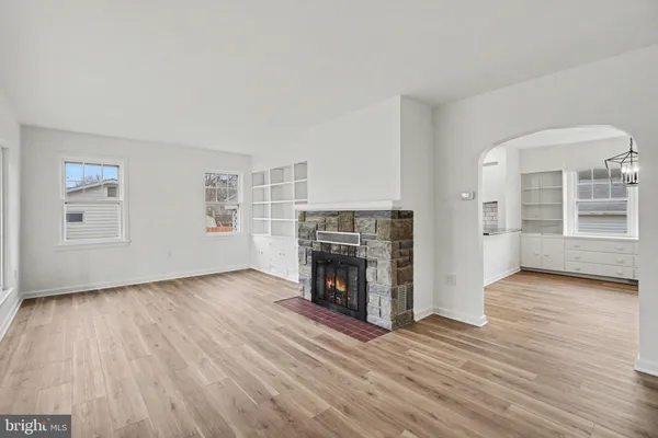 an empty room with wooden floor fireplace and windows