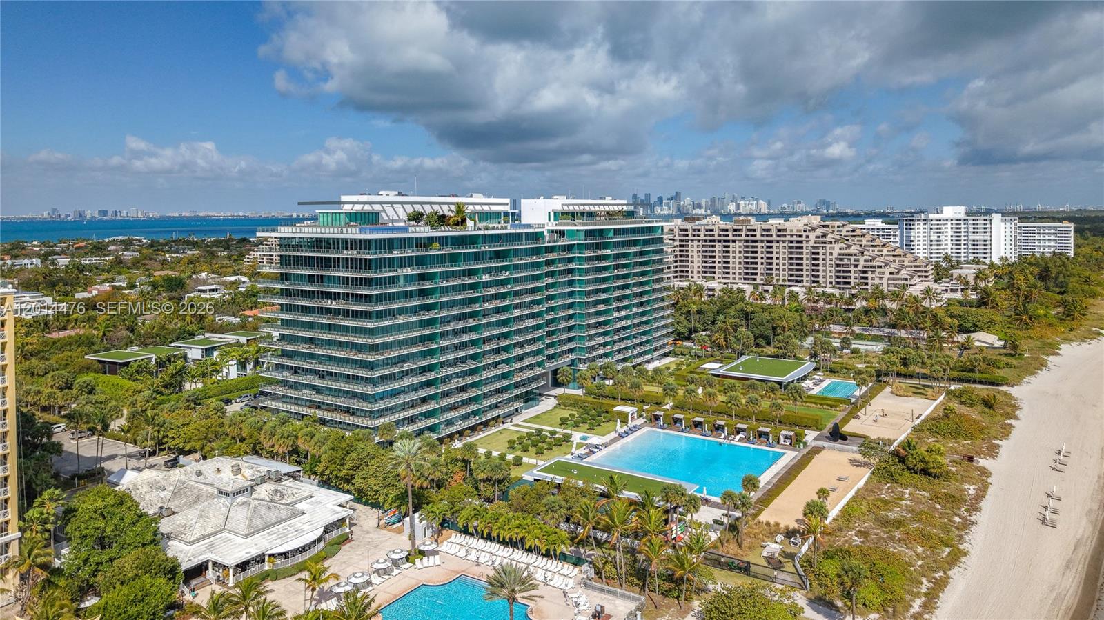 360 Ocean Drive, Unit 1106S Key Biscayne, FL 33149 - Photo 47 of 67 Aerial Exterior with Skyline Views – This elevated angle captures the building, surrounding residences, Biscayne Bay, and the distant skyline. The property is positioned within a lush coastal setting with water views in multiple directions.