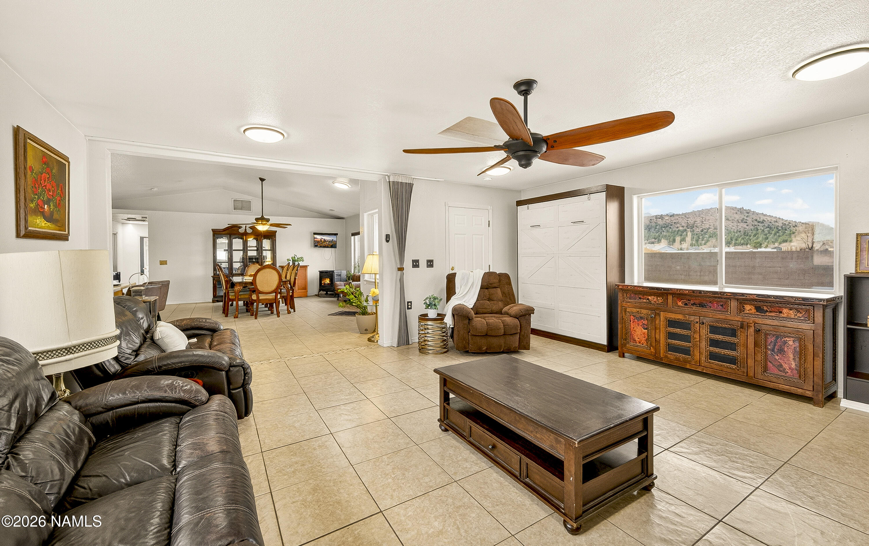 7725 Alma Road Flagstaff, AZ 86004 - Photo 15 of 38 a living room with furniture a flat screen tv and a floor to ceiling window