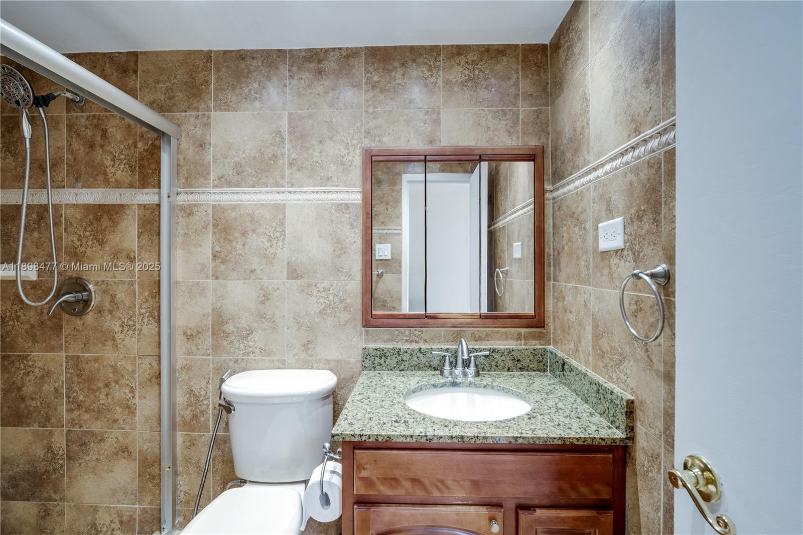 2451 Brickell Avenue, Unit 6N Miami, FL 33129 - Photo 26 of 43 a bathroom with a granite countertop sink toilet a mirror and shower