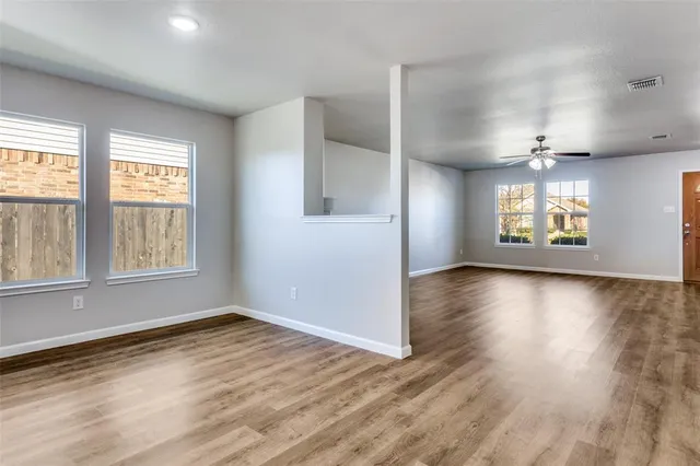 an empty room with wooden floor and windows