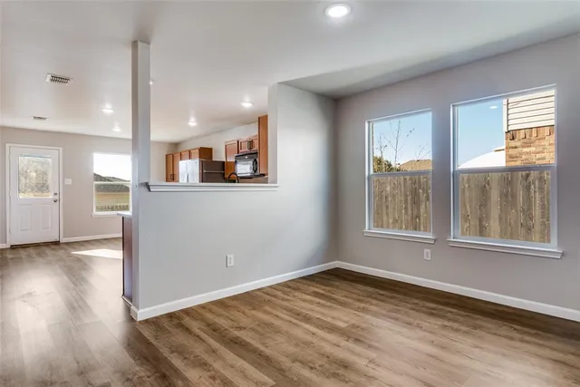 an empty room with wooden floor and windows