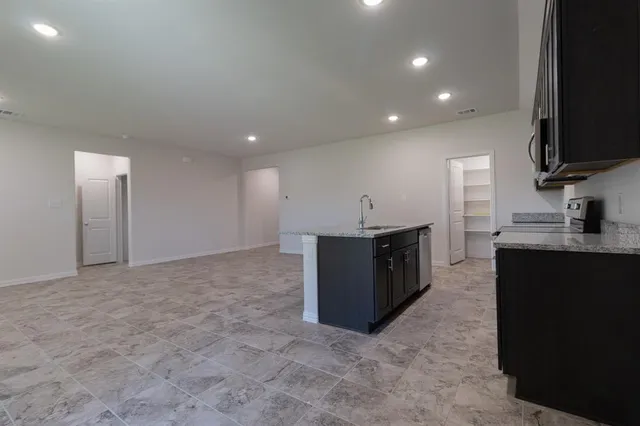 a kitchen with stainless steel appliances granite countertop a sink a stove top oven and granite counter tops