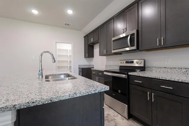 a kitchen with stainless steel appliances granite countertop a sink stove and refrigerator