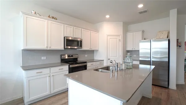 a kitchen with kitchen island granite countertop a sink a counter top space cabinets and stainless steel appliances