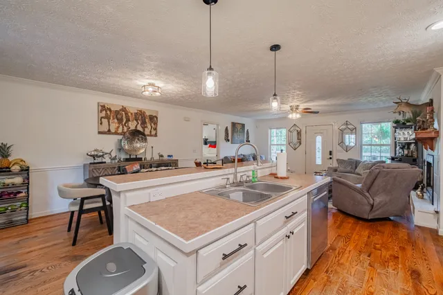 a kitchen with stainless steel appliances granite countertop a stove a refrigerator a kitchen island a dining table and chairs with wooden floor