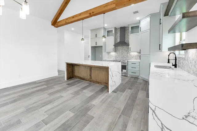 a kitchen with stainless steel appliances kitchen island granite countertop a stove a sink and a refrigerator