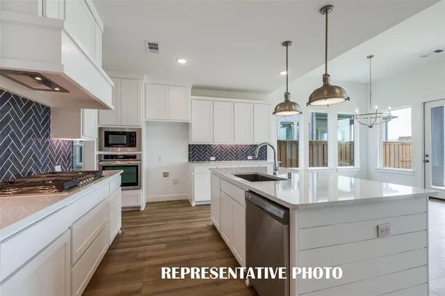a kitchen with stainless steel appliances granite countertop a sink a stove and a refrigerator
