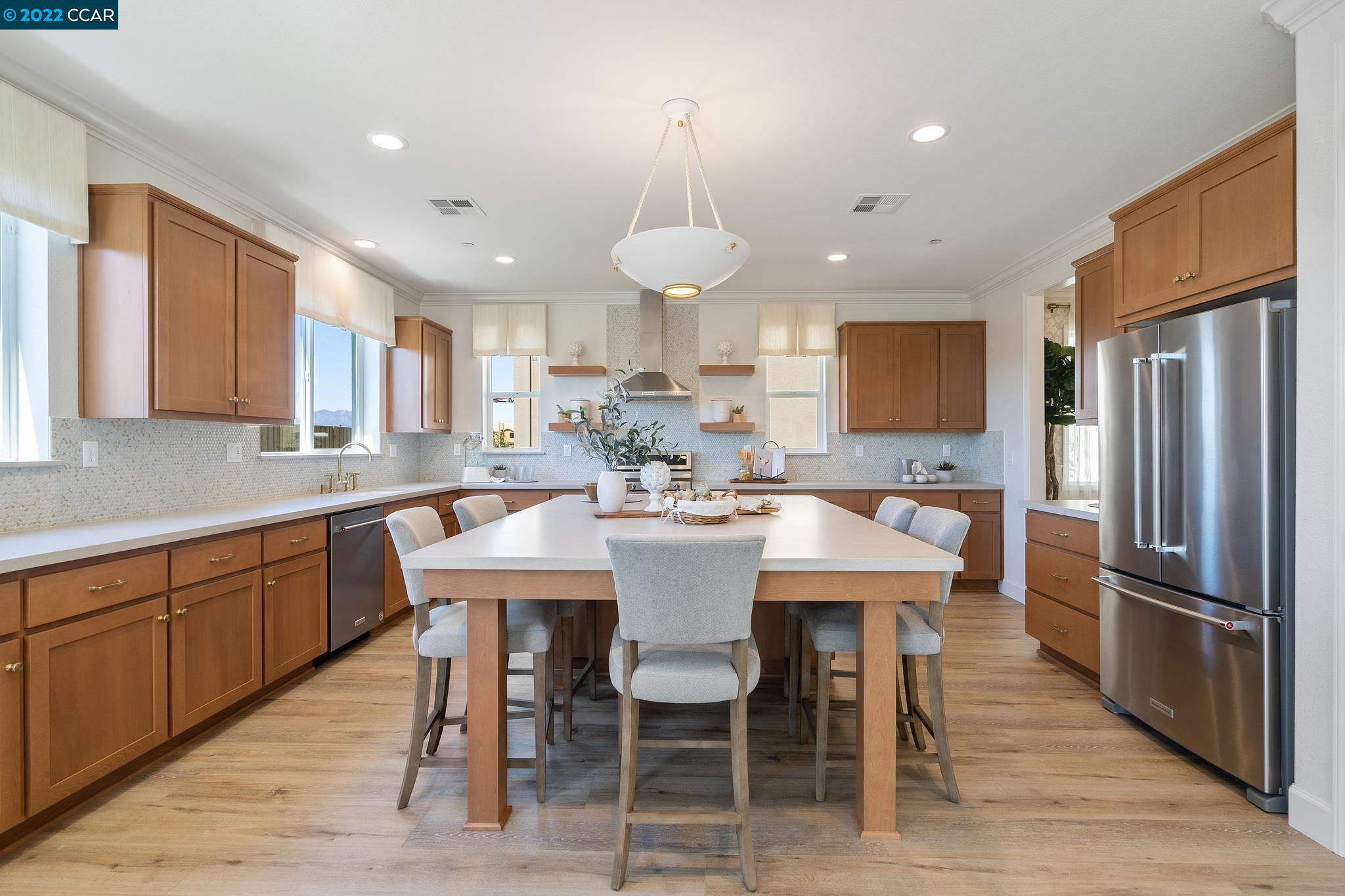 a kitchen with stainless steel appliances granite countertop a dining table chairs refrigerator sink and cabinets