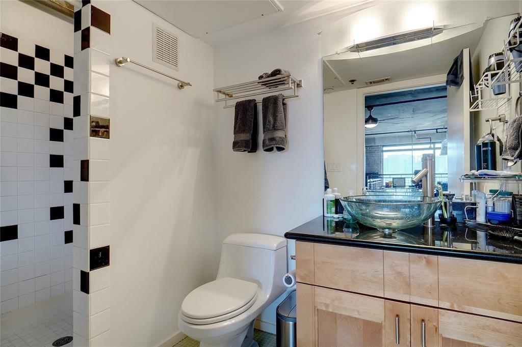 3110 Thomas Avenue, Unit 739 Dallas, TX 75204 - Photo 13 of 18 a bathroom with a granite countertop sink a toilet and shower