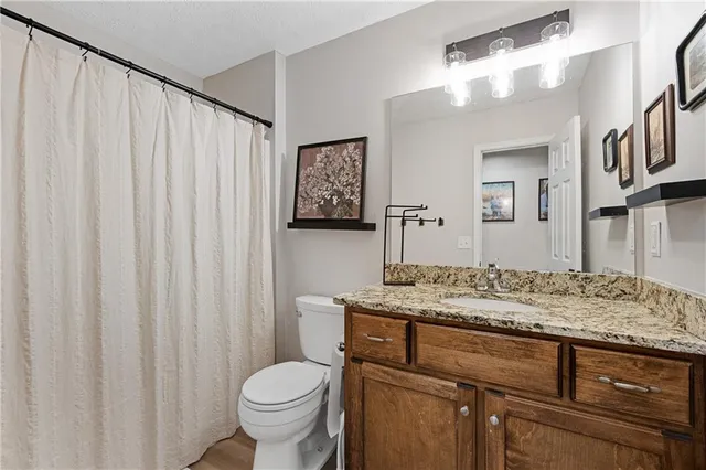 a bathroom with a granite countertop sink and a toilet