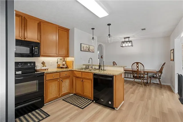 a kitchen with stainless steel appliances granite countertop a stove top oven a sink dishwasher and white cabinets with wooden floor