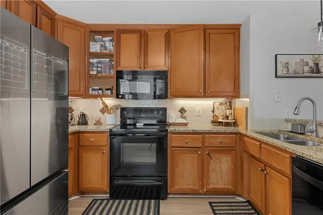 a kitchen with stainless steel appliances granite countertop a stove a sink and a refrigerator