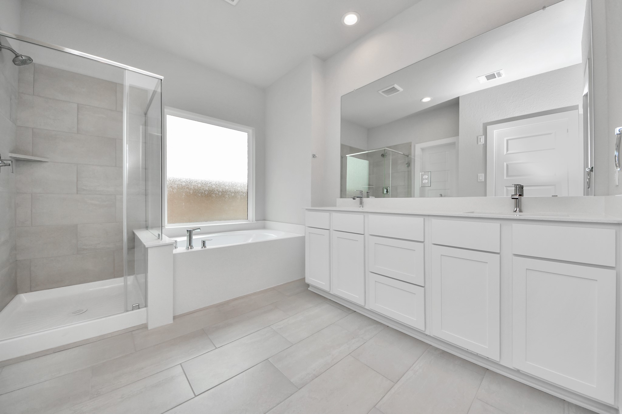 11114 Tulip Rdg Trail Houston, TX 77044 - Photo 19 of 30 Escape to a spa-like oasis in this primary bathroom. Enjoy a walk-in shower with tile surround, a separate garden tub with custom detailing, and an elegant vanity featuring light countertops, modern hardware, and beautiful vanity lights. Experience luxury and relaxation in every detail. Sample photo of completed home with similar floor plan. Actual colors and selections may vary.