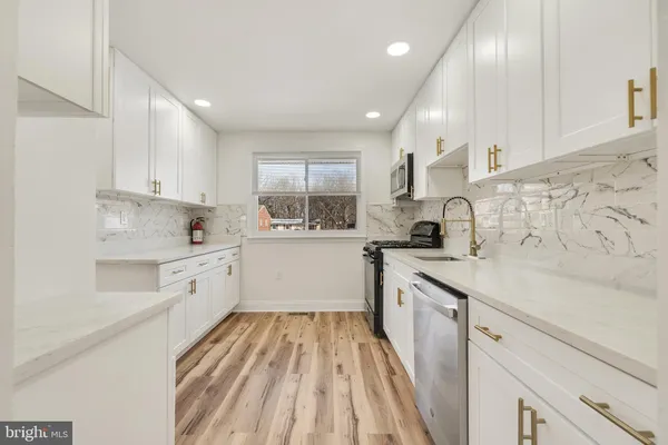 a kitchen with stainless steel appliances granite countertop a stove a sink and white cabinets