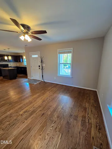a view of an empty room with window and wooden floor