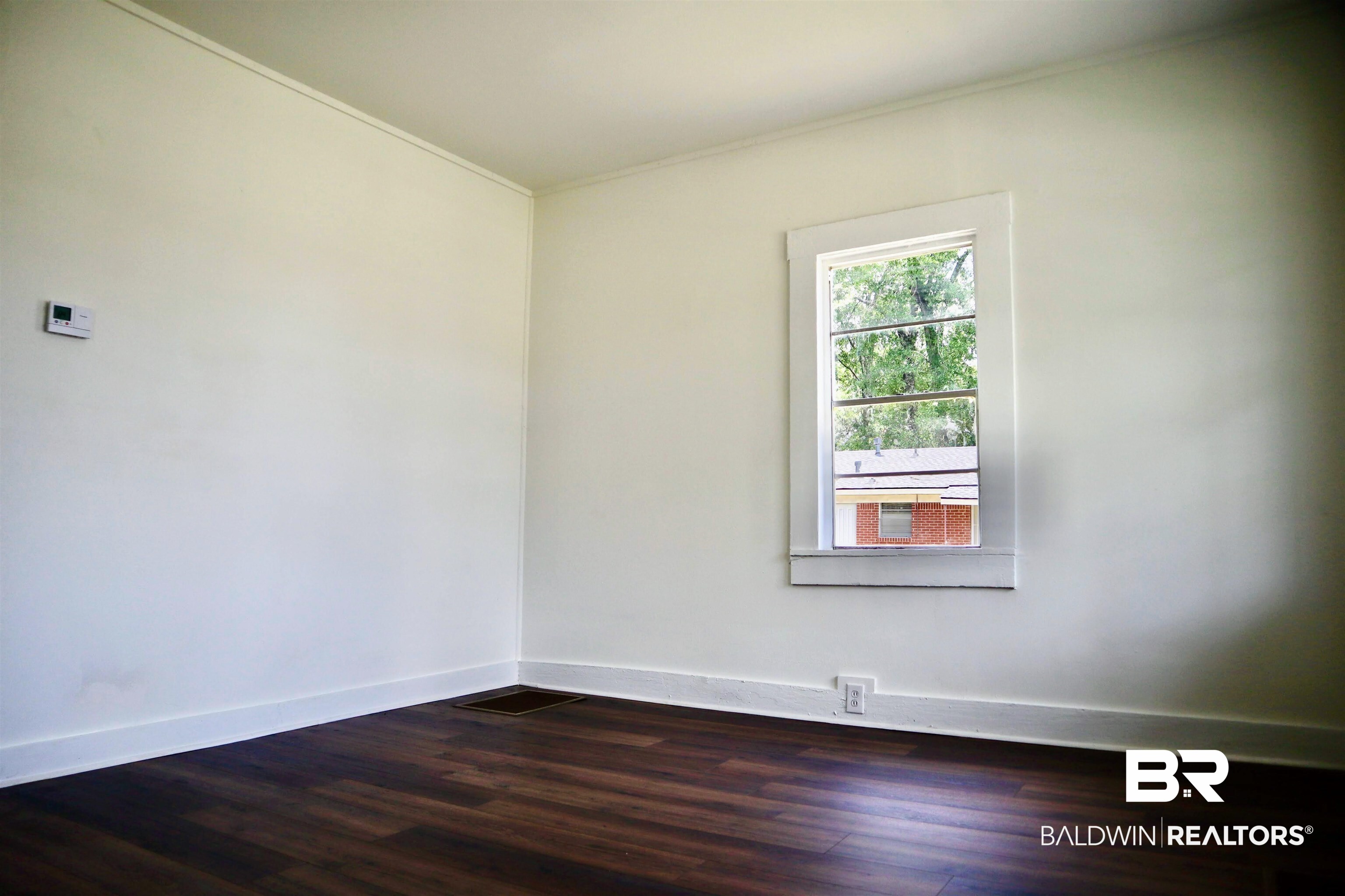 1009 Baltimore Street Mobile, AL 36605 - Photo 6 of 17 Empty room featuring dark wood-style flooring and crown molding