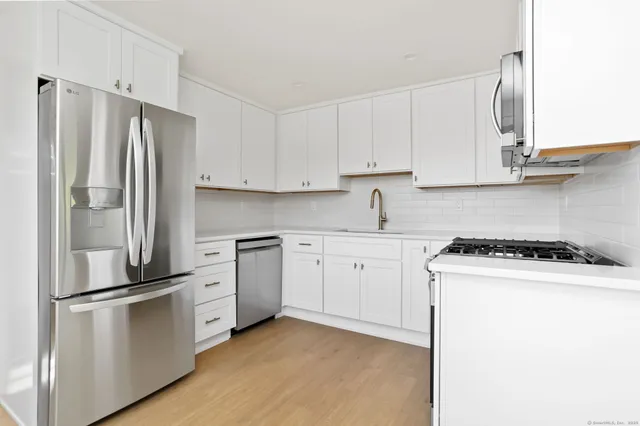 a kitchen with stainless steel appliances white cabinets and a refrigerator