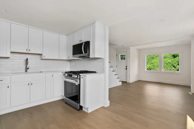 a kitchen with granite countertop a stove a sink and a microwave