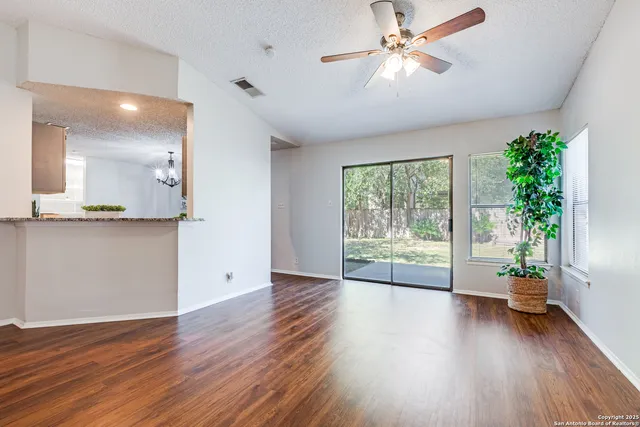 a view of empty room with wooden floor and fan