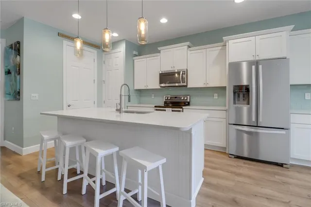 a kitchen with stainless steel appliances granite countertop a stove top oven a sink a dining table and chairs with wooden floor