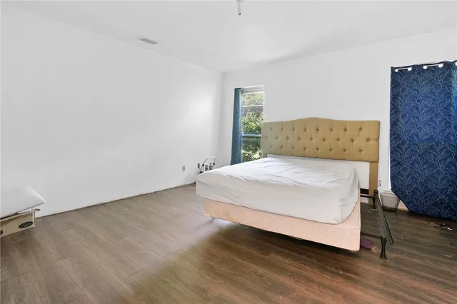 a spacious bedroom with a bed and wooden floor